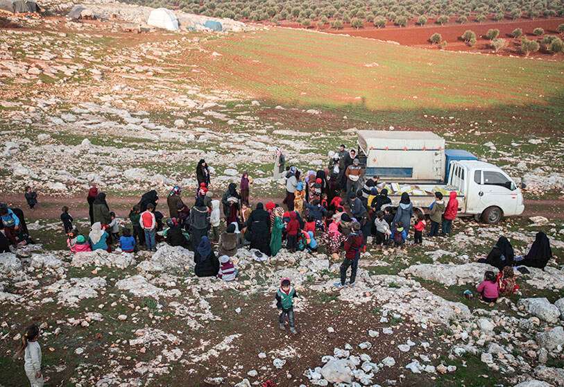Desplazados sirios del sur de la provincia de Idlib reciben ayuda alimentaria de un camión en el campo al oeste de la ciudad de Dana, en la región noroccidental de Siria, el 23 de diciembre de 2019