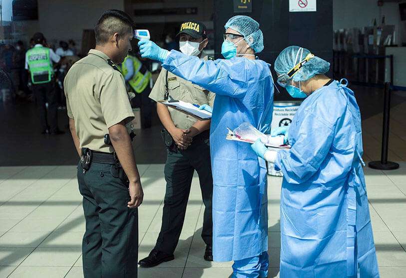 Un médico mide la temperatura de un oficial de Policía como precaución contra la propagación del nuevo coronavirus en el aeropuerto de Lima