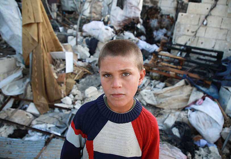 Un niño junto a una tienda de campaña dañada tras el bombardeo del régimen sirio sobre un campamento improvisado en la aldea de Qah