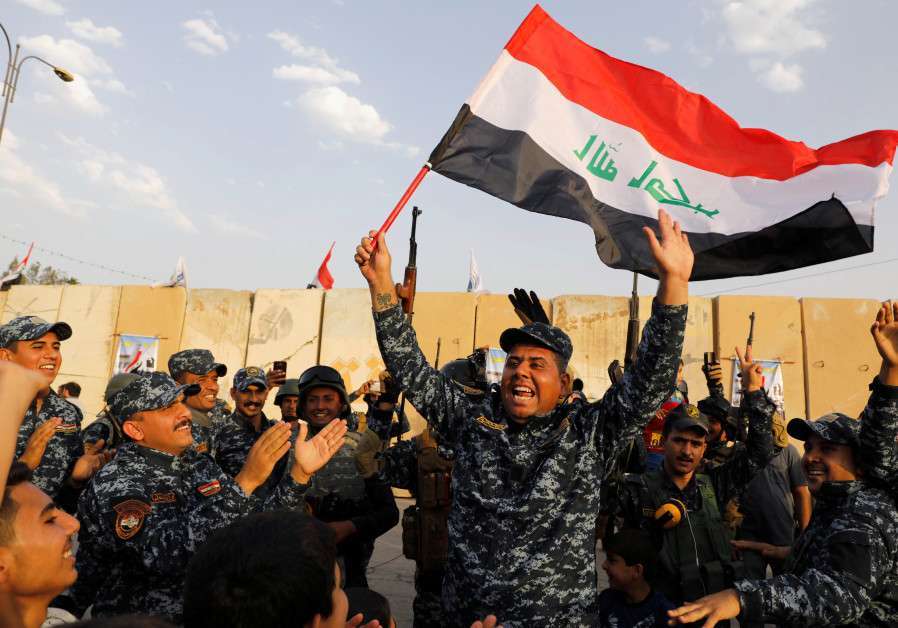 Un miembro de la Policía Federal iraquí ondea una bandera iraquí mientras celebran la victoria de las operaciones militares contra los militantes del Estado Islámico en el oeste de Mosul, Iraq, 2 de julio de 2017.
