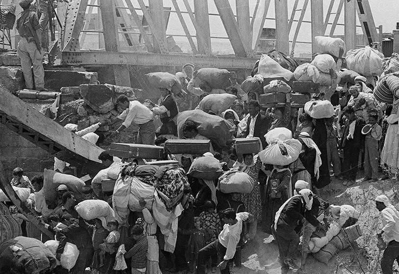 En esta foto de archivo del 22 de junio de 1967, refugiados palestinos llevan sus pertenencias mientras se preparan para cruzar el destrozado puente Allenby sobre el río Jordán desde la parte de Jordania ocupada por Israel AP/BERNARD FRYE