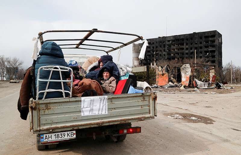 Los evacuados que huyen del conflicto entre Ucrania y Rusia se sientan en la carrocería de un vehículo de carga mientras esperan en una fila para salir de la sitiada ciudad portuaria del sur de Mariúpol