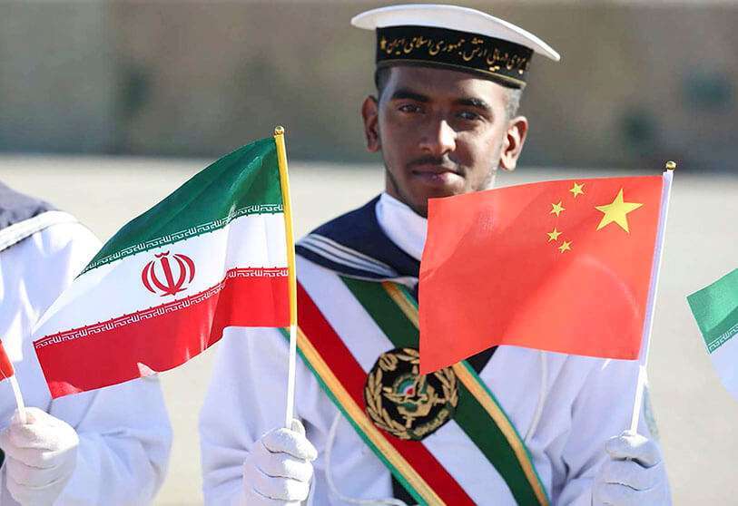 Un marinero iraní sosteniendo las banderas nacionales iraní y china durante una ceremonia en Chabahar, en el Golfo de Omán, durante los ejercicios navales conjuntos de Irán, Rusia y China