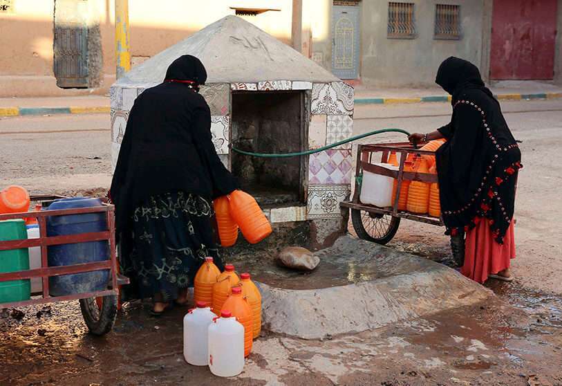 Mujeres marroquíes llenando contenedores con agua de una manguera, en Zagora, en el sureste de Marruecos