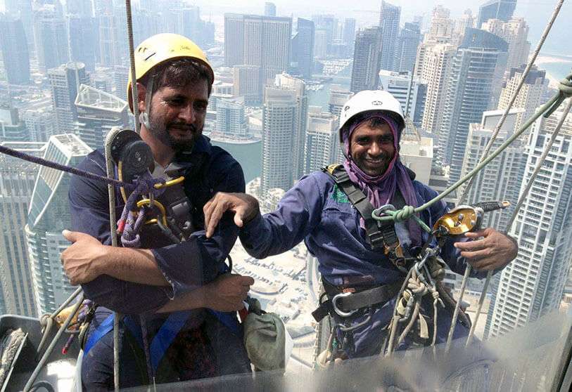 Limpiadores de ventanas pakistaníes trabajan en la fachada de un edificio en el emirato del Golfo de Dubai el 6 de septiembre de 2014