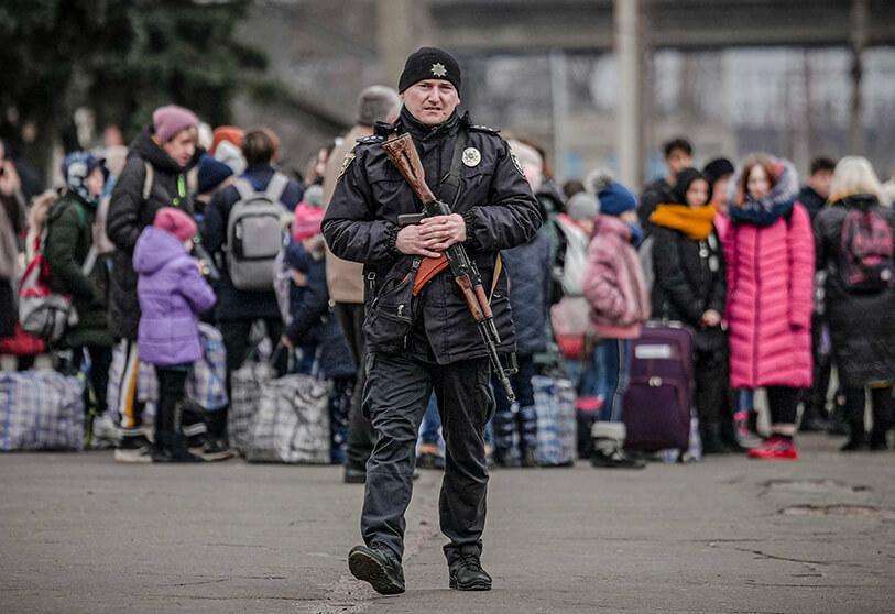 AP/VADIM GHIRDA - Un agente de Policía ucraniano con un rifle de asalto camina por un andén rodeado de gente que espera un tren con destino a Kiev en Kostiantynivka, región de Donetsk, este de Ucrania, el jueves 24 de febrero de 2022