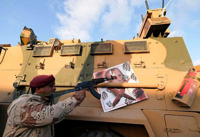 Un miembro del Ejército Nacional Libio (LNA), comandado por Jalifa Haftar, apunta con su arma a la imagen del presidente turco Recep Tayyip Erdogan colgado de un vehículo militar blindado turco