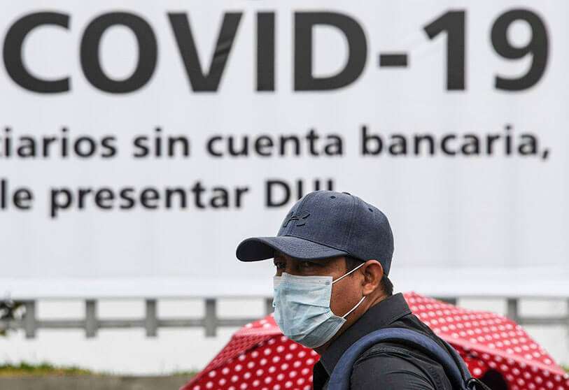 Un hombre lleva una máscara facial contra la propagación del nuevo coronavirus mientras espera entrar en un banco para recibir un bono de 300 dólares estadounidenses en Santa Tecla, El Salvador