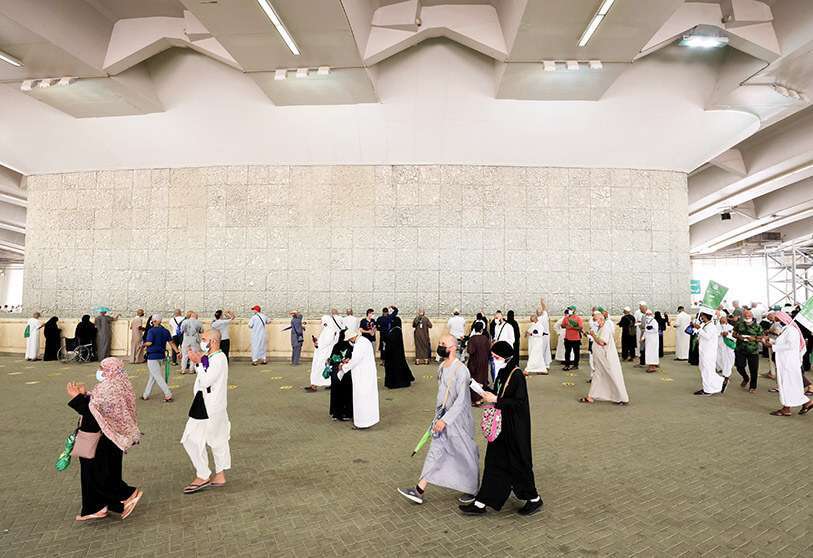Peregrinos musulmanes pasan, mientras otros peregrinos arrojan piedras a un pilar que simboliza a Satanás durante la peregrinación anual del Haj, en medio de la pandemia de la enfermedad del coronavirus (COVID-19), en Mina, cerca de la ciudad santa de La Meca, Arabia Saudí, el 21 de julio de 2021 PHOTO/REUTERS