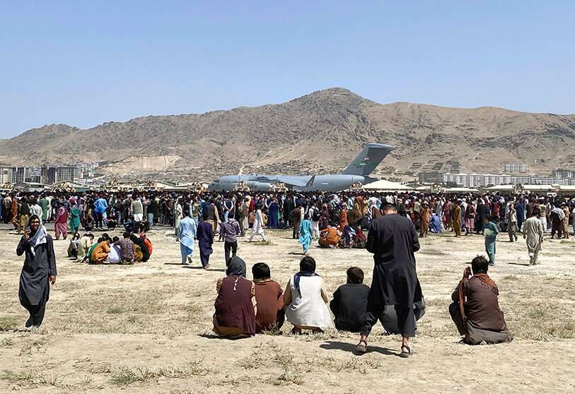 Cientos de personas se reúnen cerca de un avión de transporte C-17 de la Fuerza Aérea de Estados Unidos en el perímetro del aeropuerto internacional de Kabul, Afganistán, el lunes 16 de agosto de 2021. El lunes, el ejército y las autoridades estadounidenses se concentraron en el aeropuerto de Kabul, donde miles de afganos atrapados por la repentina toma del poder por parte de los talibanes se abalanzaron sobre la pista y se aferraron a los aviones militares estadounidenses desplegados para sacar al personal de la embajada de Estados Unidos