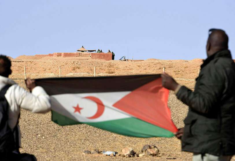 PHOTO/AFP - Un homme sahraoui tient un drapeau du Front Polisario dans la région d'Al-Mahbes, dans le Sahara occidental contrôlé par le Polisario.