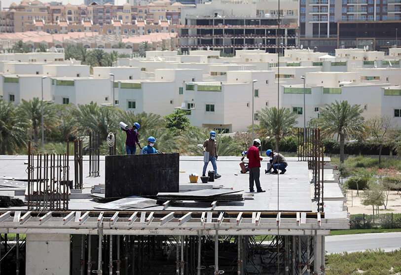 Trabajadores con máscaras protectoras trabajan en una obra de construcción residencial