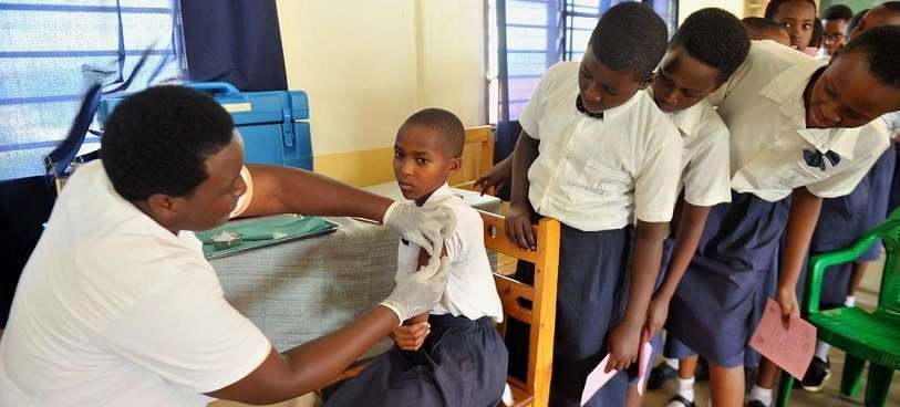 UNICEF/Laurent Rusanganwa - Una joven de Rwanda recibe su vacuna contra el Virus del Papiloma Humano mientras sus compañeros de clase miran atentamente