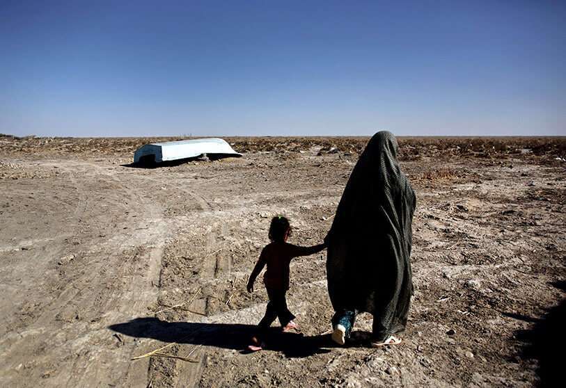 Una mujer iraní caminando con su hija junto a un barco abandonado en el pueblo de Sikh Sar, en el humedal de Hamoon, cerca de la ciudad de Zabol, en la provincia sudoriental de Sistán-Baluchistán, fronteriza con Afganistán AFP/ BEHROUZ MEHRI